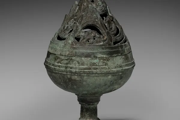 Ancient Chinese bronze incense burner with a perforated mountain-shaped lid, decorated with mythical creatures and covered in green patina.