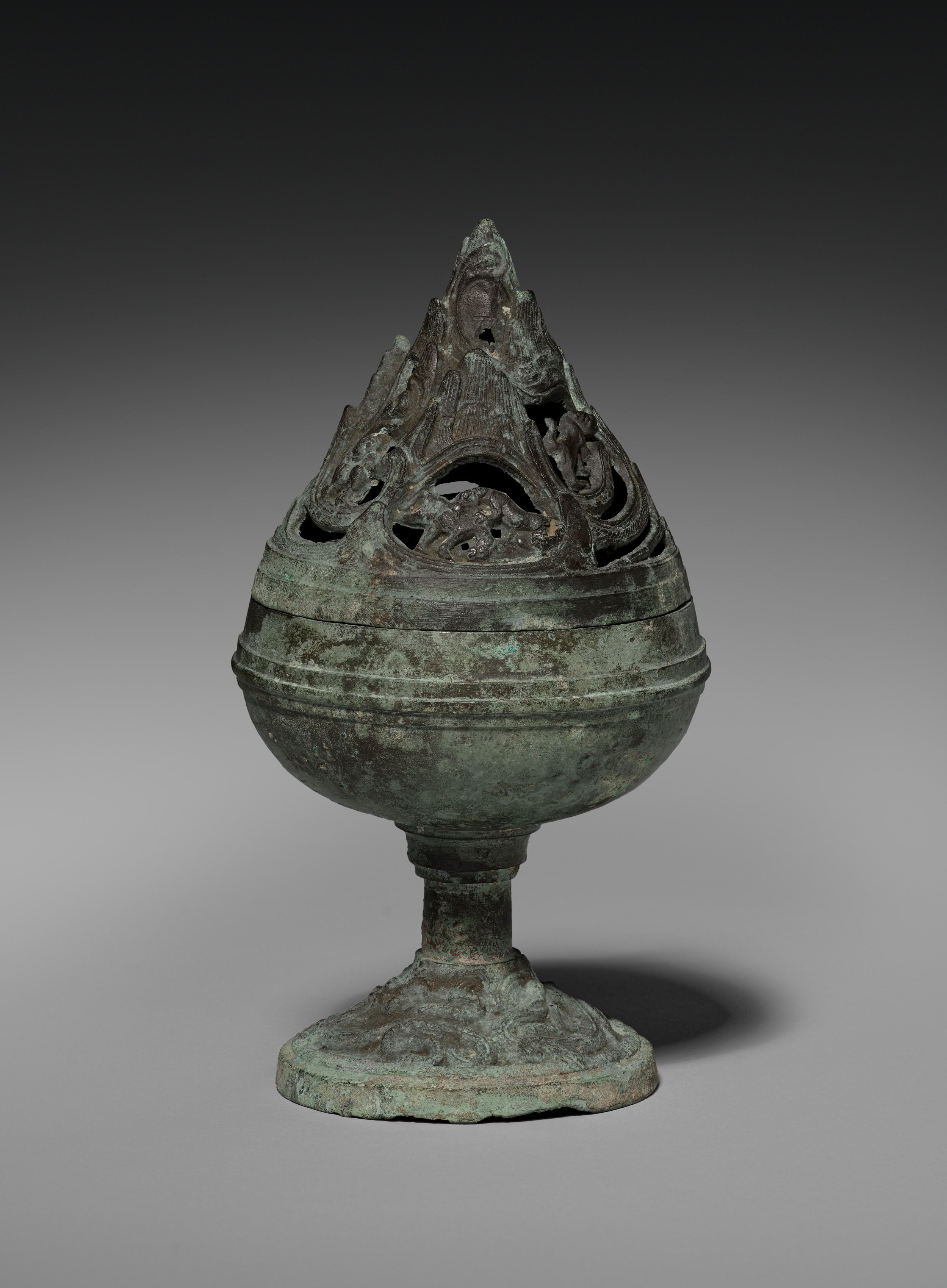 Ancient Chinese bronze incense burner with a perforated mountain-shaped lid, decorated with mythical creatures and covered in green patina.