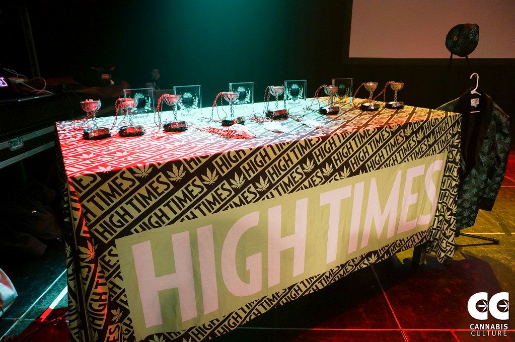 Cannabis Cup trophies arranged on a table covered with a High Times banner
