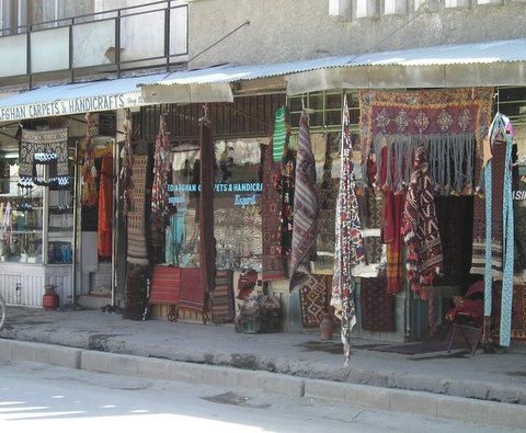 Carpet and handicraft shops with woven rugs hanging outside on Chicken Street in Kabul.