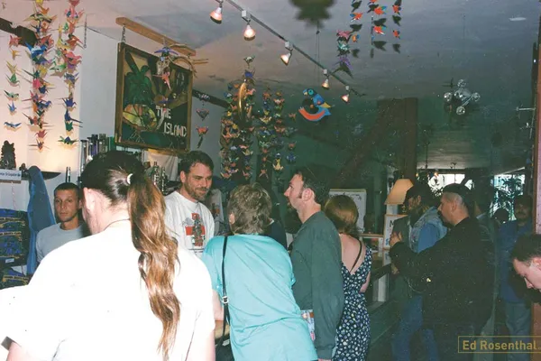 Historical color photograph showing patients gathered around a counter inside the San Francisco Cannabis Buyers Club in 1994, with handmade decorations hanging from the ceiling.