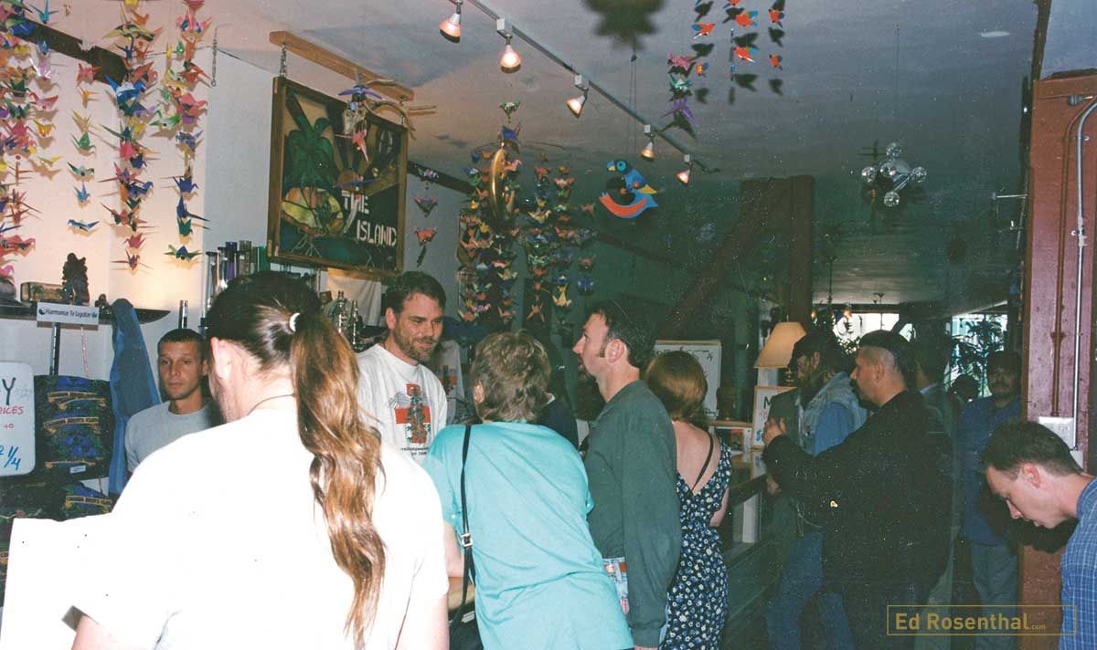 Historical color photograph showing patients gathered around a counter inside the San Francisco Cannabis Buyers Club in 1994, with handmade decorations hanging from the ceiling.