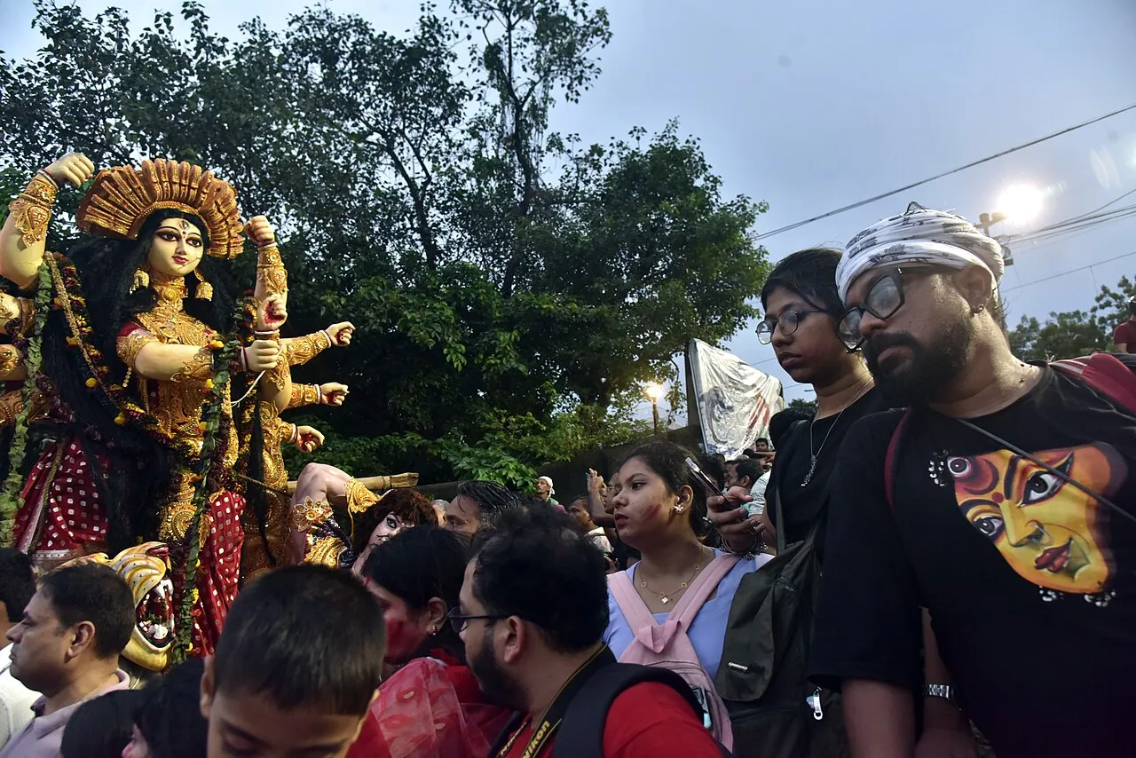 Crowds and decorated images of Durga at a ghat in Kolkata during the immersion