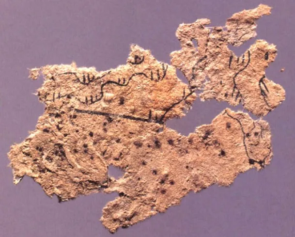 A small, torn piece of fibrous paper with lines and marks in black ink.
