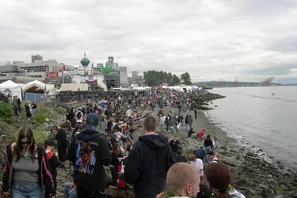 A large crowd along the rocky beach at Seattle Hempfest