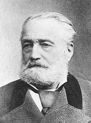 Black-and-white photograph of an elderly man with a white beard and swept-back hair