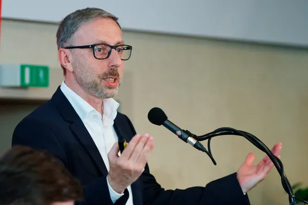 Czech drug policy expert Jindřich Vobořil wearing glasses and a dark suit, speaking into a microphone and gesturing with his hand.
