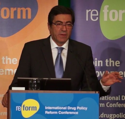 A man in a dark suit and tie speaking at a lectern in front of conference banners