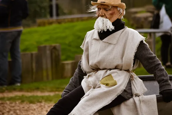 Traditional Lithuanian Hemp Man character wearing a straw hat, long white beard, and rough linen clothing during an Užgavėnės celebration.