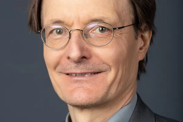 Portrait of a man with grey hair and glasses in a dark jacket