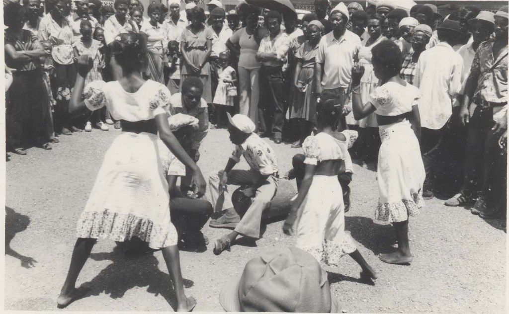 Historical black-and-white photograph of Jamaican Kumina dancers performing alongside traditional drummers.