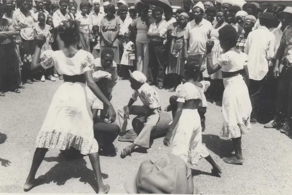 Historical black-and-white photograph of Jamaican Kumina dancers performing alongside traditional drummers.