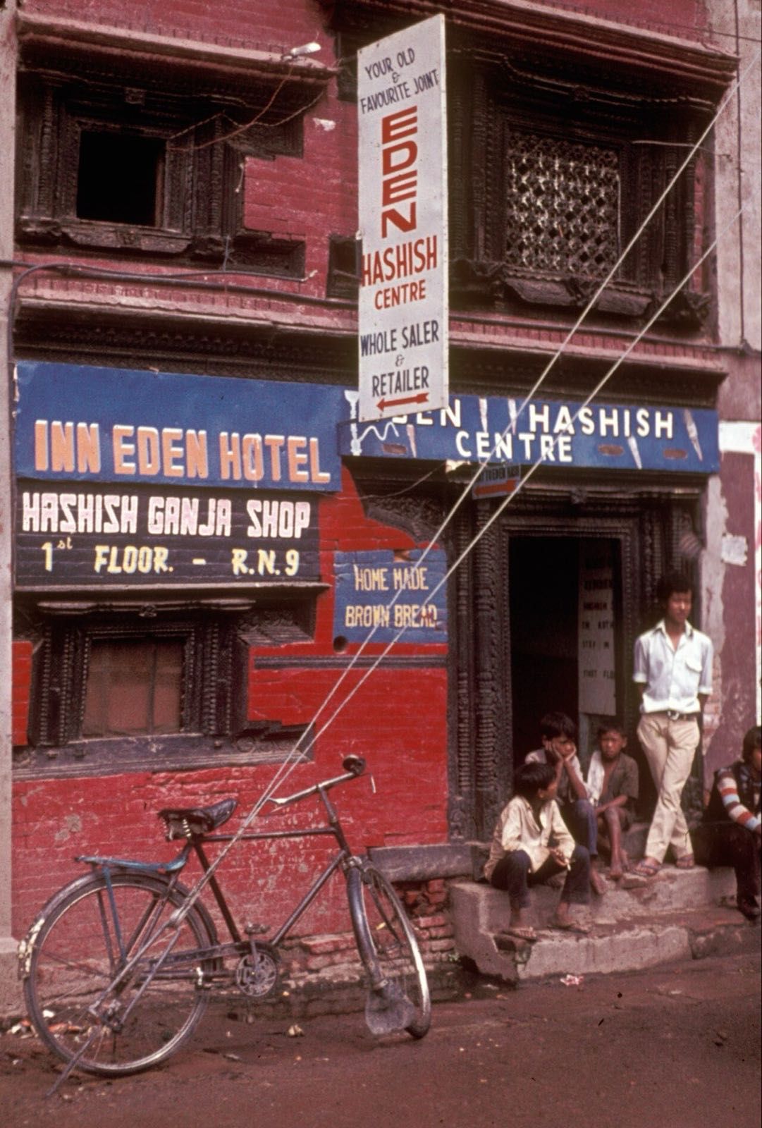 Customers sit outside Kathmandu's Eden Hashish Centre beneath signs advertising hashish, ganja and lodging
