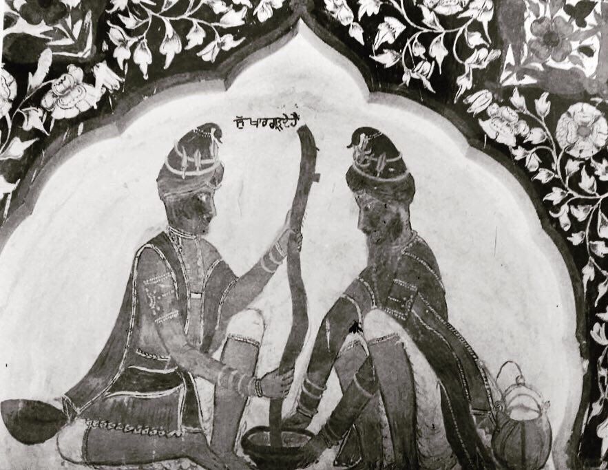 A wall painting of two Nihang Sikhs in blue grinding cannabis in a large mortar