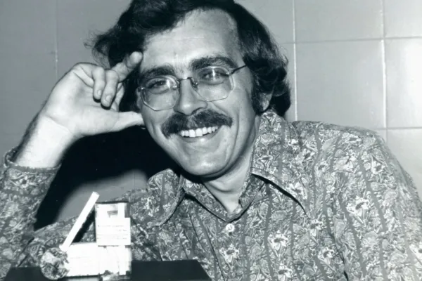 Black-and-white photograph of Robert Randall smiling in glasses beside his first legal supply of government-provided marijuana cigarettes in November 1976.