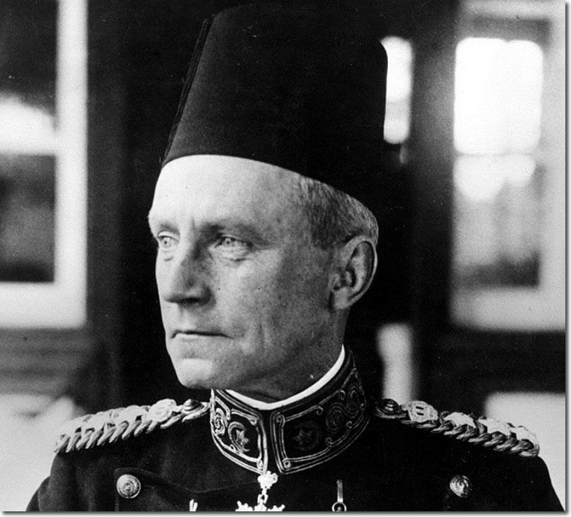 Black-and-white portrait of a man in a fez and a dark uniform with embroidered collar and epaulettes, looking to one side