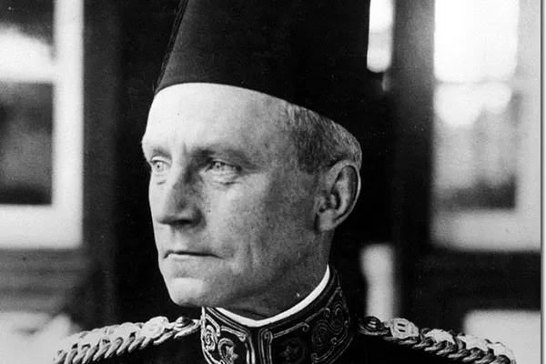 Black-and-white portrait of a man in a fez and a dark uniform with embroidered collar and epaulettes, looking to one side