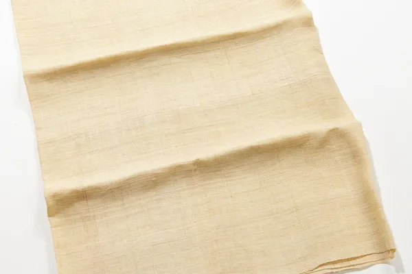 A folded length of coarse, pale yellow hemp cloth