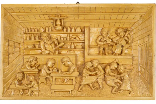 Carved wooden relief depicting a lively Polish village tavern, with traditional musicians, dancing couples, and villagers gathered around tables.