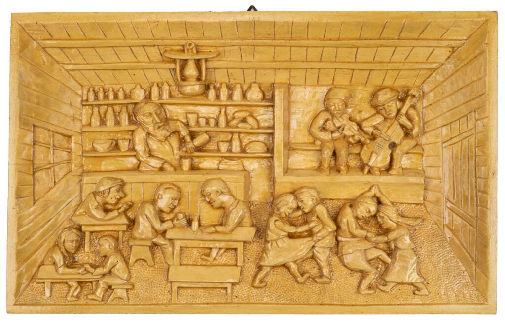 Carved wooden relief depicting a lively Polish village tavern, with traditional musicians, dancing couples, and villagers gathered around tables.