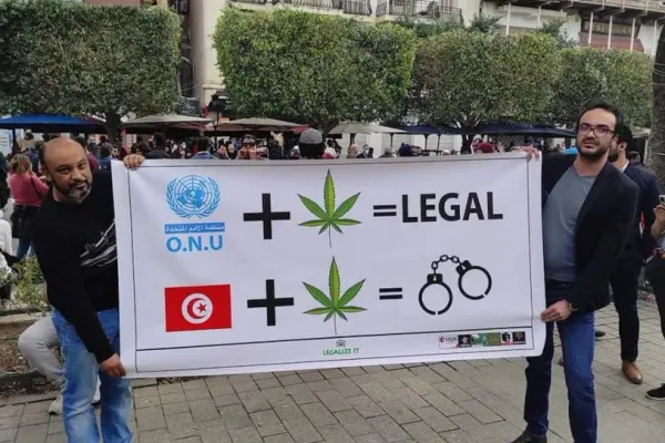 Tunisian cannabis legalization activists holding a banner featuring cannabis leaves and handcuffs to criticize punitive drug laws.